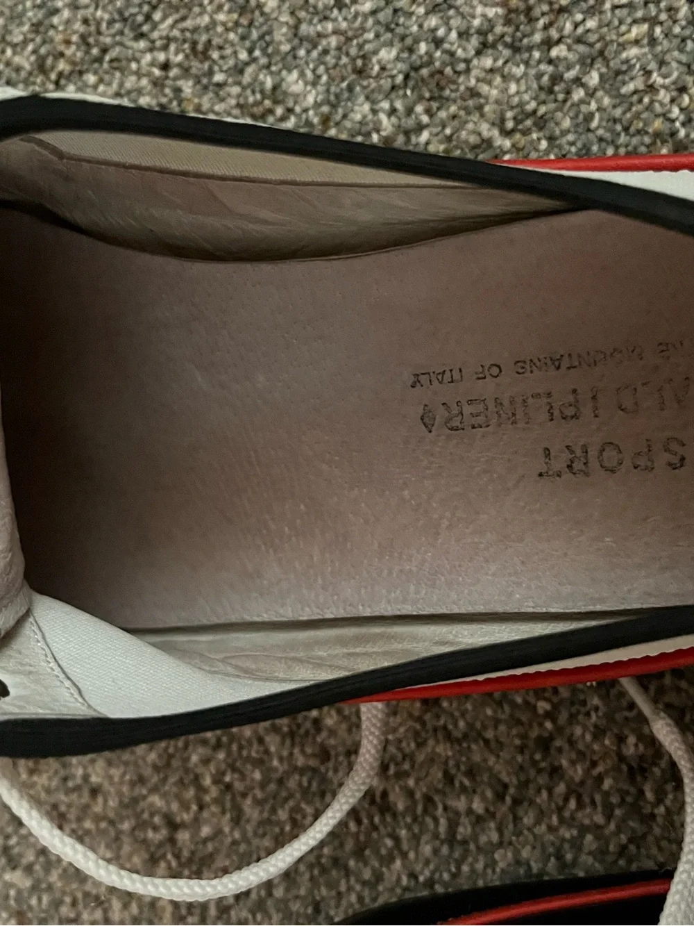 Donald J Pliner white canvas and black leather sneakers with red trim.